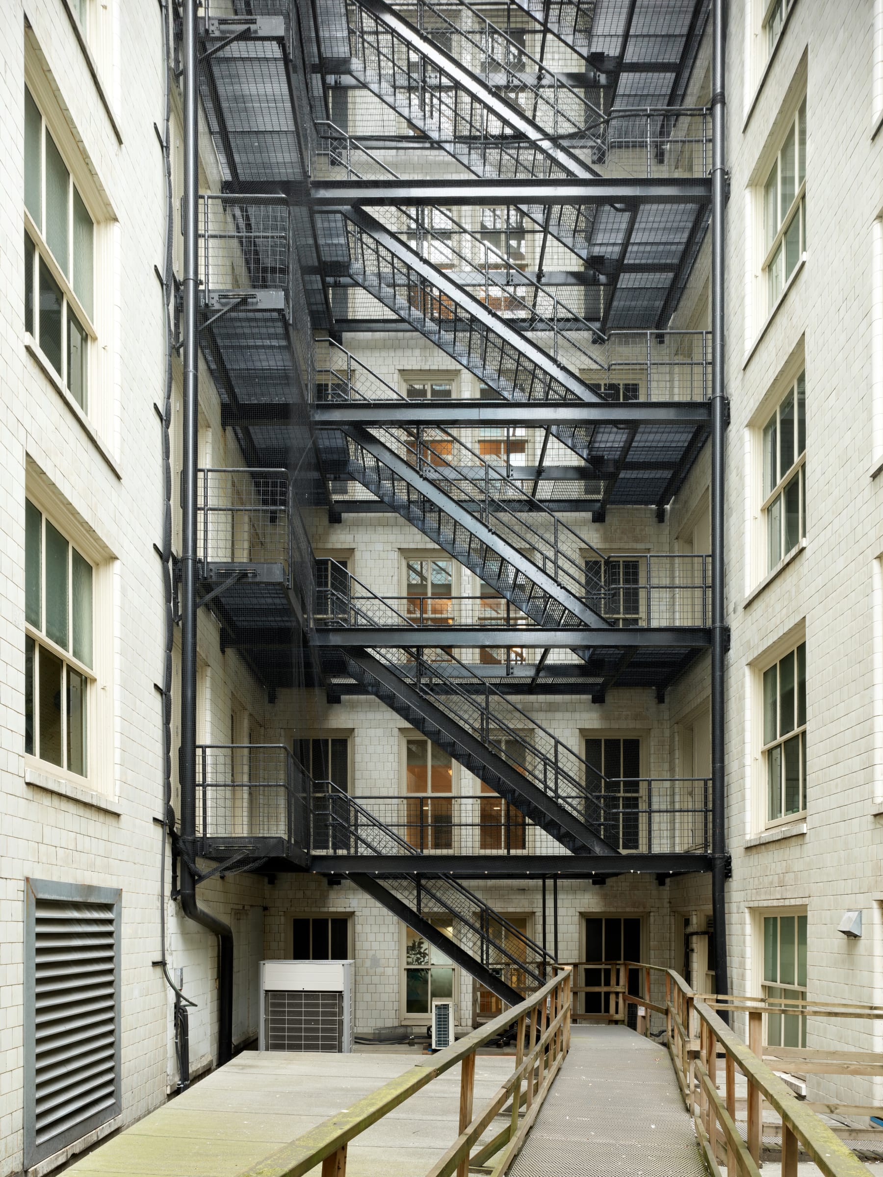 Black fire escapes zigzagging up the glazed brick light well